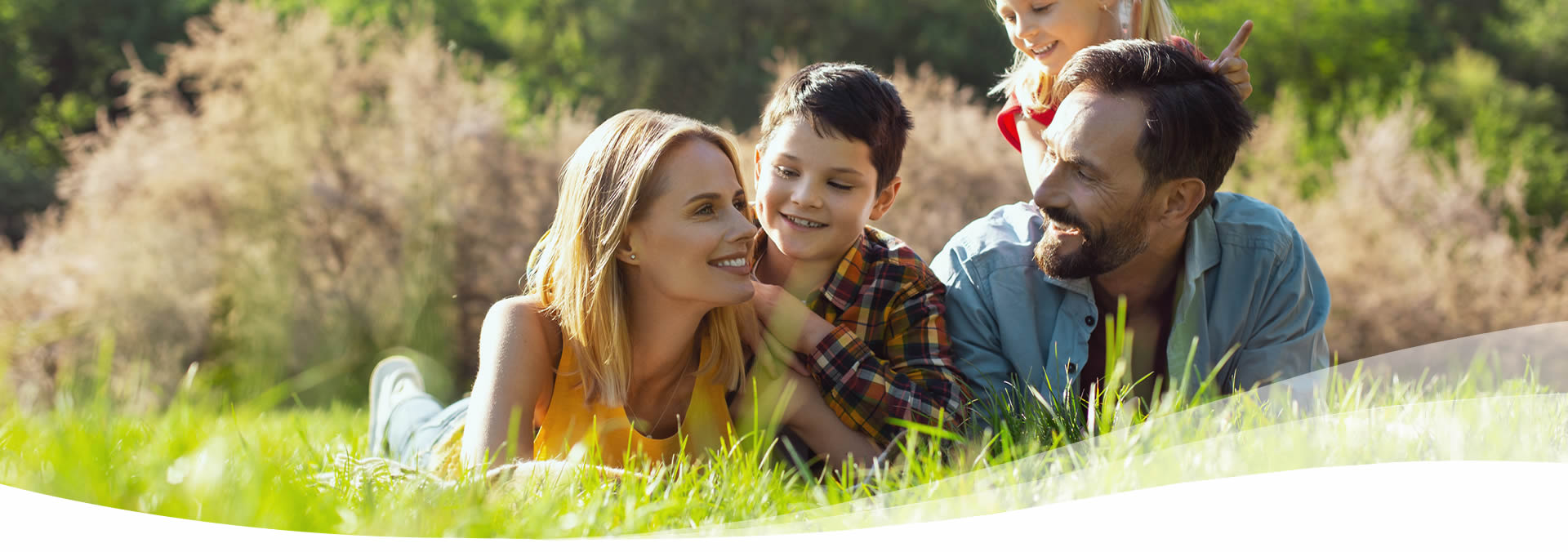 family laying down in the grass